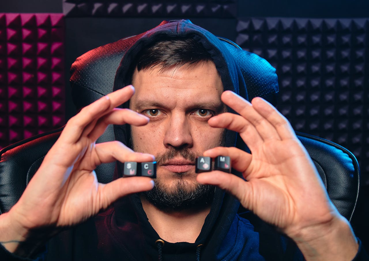 Man in hoodie holding alphabet keys spelling 'SCAM', symbolizing cybersecurity threat.